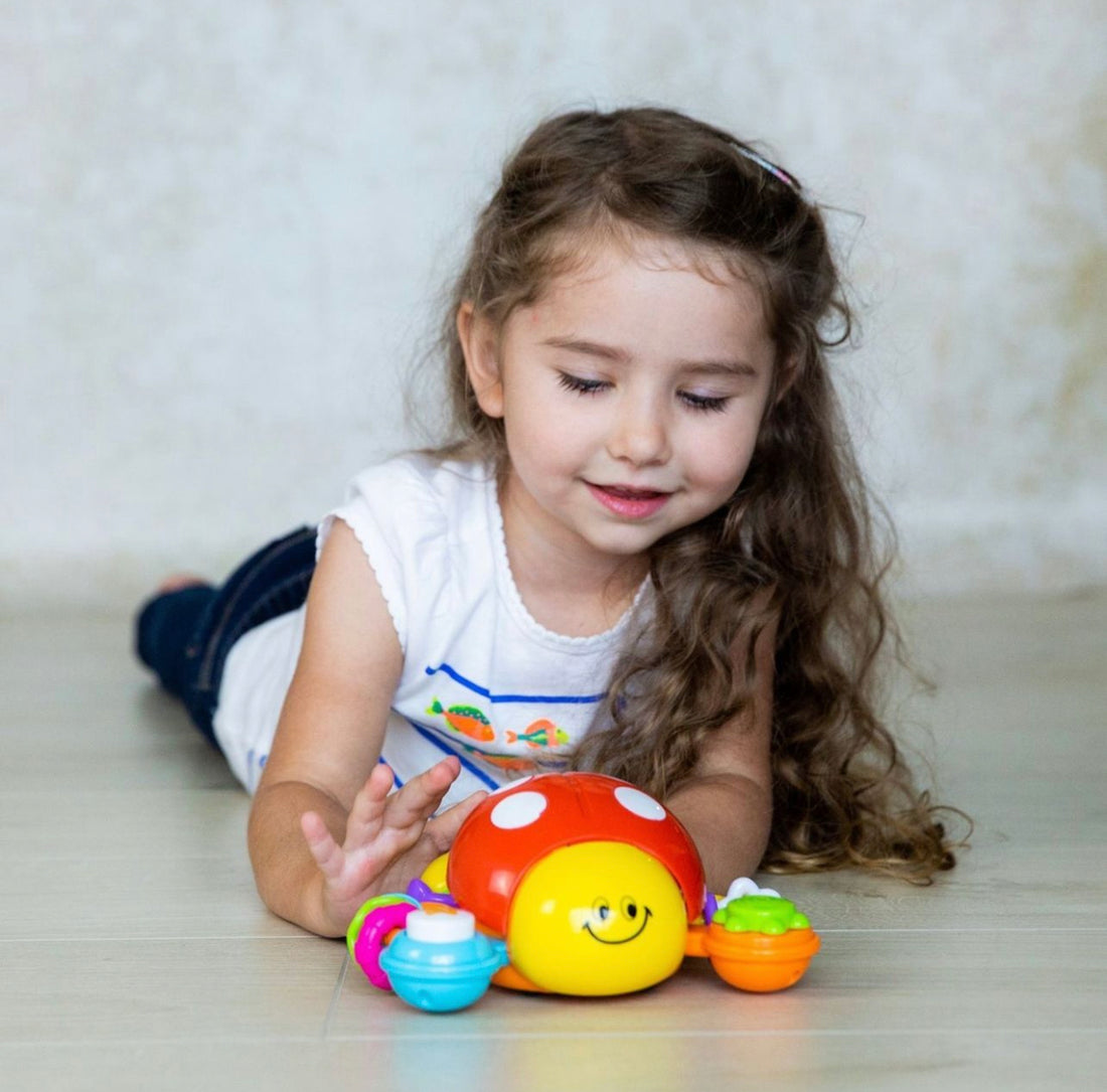 A young child exploring and learning with Lilly the Bug, demonstrating the toy's educational benefits in developing cognitive and motor skills.